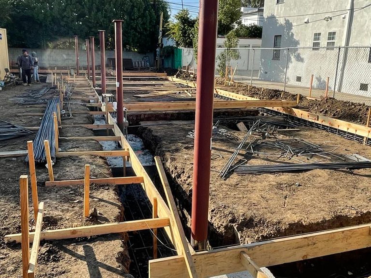 Footings, formwork, rebar, and structural steel columns set on a ground-up residential foundation