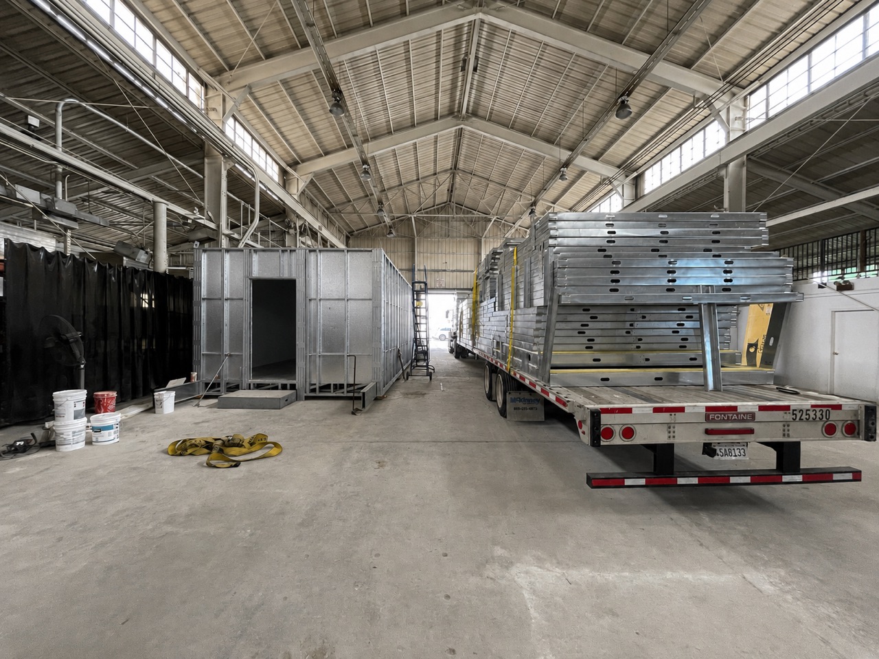 Light gauge steel wall panels loaded for delivery beside a volumetric modular unit inside the Cal Steel fabrication facility