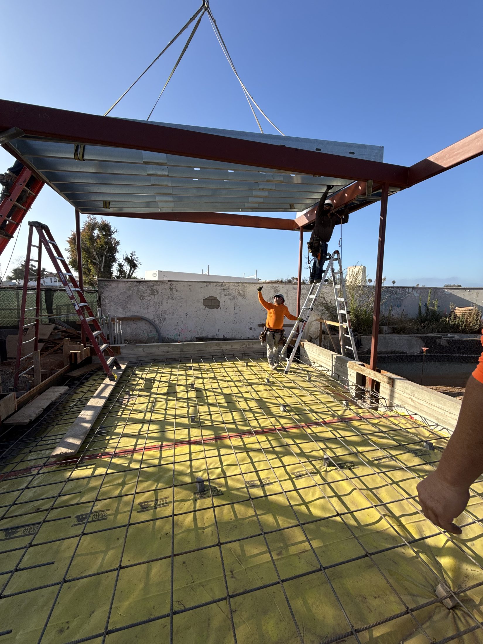 Ironworkers craning a structural steel beam into place in the field