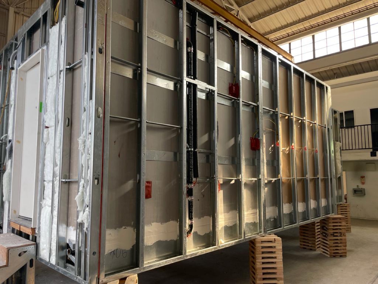 Steel-framed volumetric housing modules lined up on the factory floor