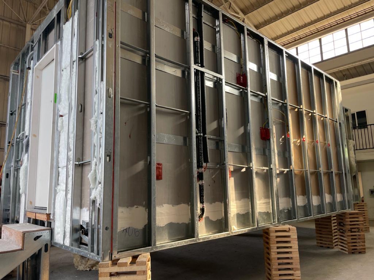 A steel-framed volumetric module with MEP and fire sprinkler lines roughed in